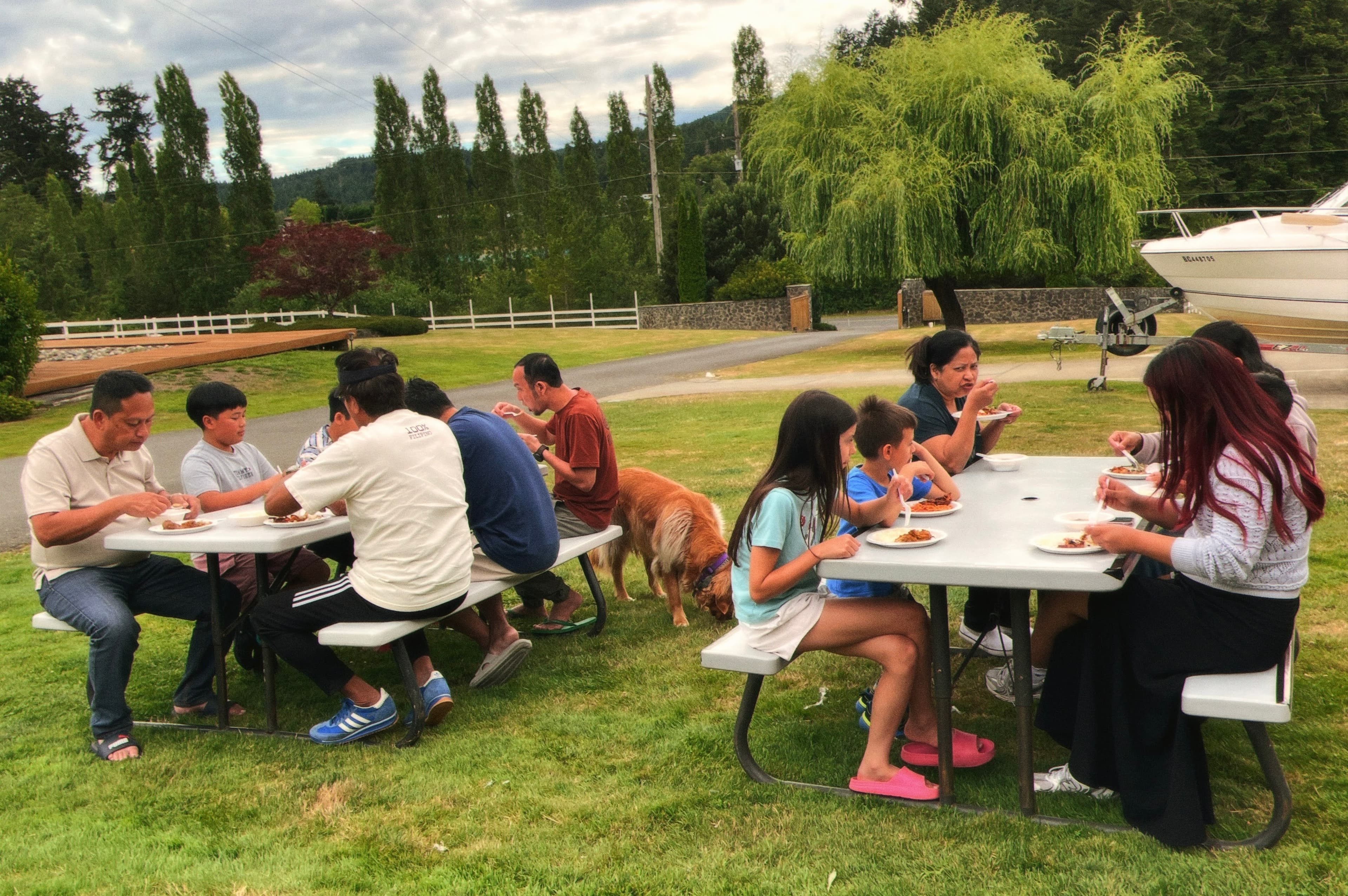 Adults and children sharing a meal at picnic tables outdoors
